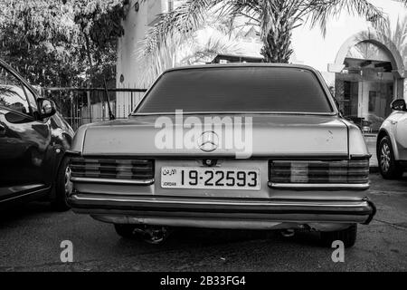 Aqaba, JORDANIEN - 31. JANUAR 2020: Der Pkw Retro Mercedes-Bentz wird im sonnigen Wintertag draußen auf der Straße abgestellt. Schwarz-Weiß-Tiefpunkt mit Fokus auf jordanischer Platte Stockfoto