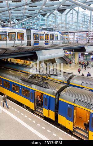 Den Haag, Niederlande - 15. Januar 2020: Pendler, die auf einem zweistufigen Bahnsteig innerhalb des Zentralbahnhofs in Der auf Züge und Straßenbahnen warten Stockfoto