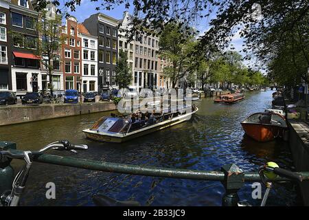 Tourboats, die auf dem Stadtkanal Amsterdam Niederlande unterwegs sind Stockfoto