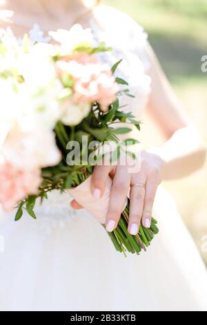 Schwerpunkt auf goldenem Trauring, Brautstrauß mit Rosen. Stockfoto