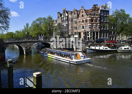 Tourboat unter der Bogenbrücke Amsterdam Niederlande Stockfoto