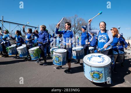 Mitglieder der Fogo Azul All-female Drumline Marching Band wärmen sich auf, bevor sie in der St. Patrick's Day Parade für Alle in Sunnyside, Queens, New marschieren Stockfoto