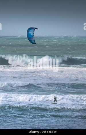 Ein einsamer Kitesurfer, der den starken Wind von Storm Jorge in Fistral in Newquay in Cornwall genießt. Stockfoto