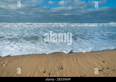 Eine eintreffende Welle, die sanft am Strand von Fistral in Newquay in Cornwall fließt. Stockfoto