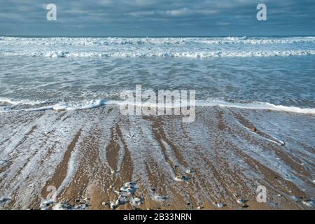 Die eintreffenden Wellen strömten sanft am Strand von Fistral in Newquay i Cornwall. Stockfoto