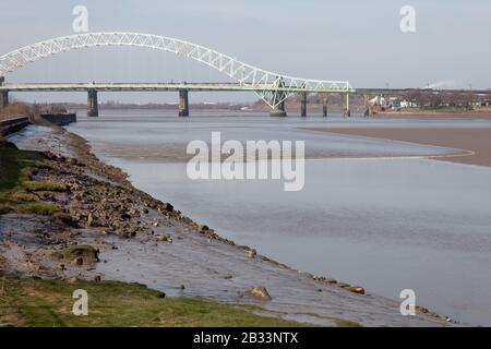 Die Mersey Tidal Bore von Wigg Island in Runcorn aus gesehen, kurz nachdem sie die Silver Jubilee Bridge passiert hat. Die Bohrung tritt manchmal auf den höchsten Gezeiten auf Stockfoto