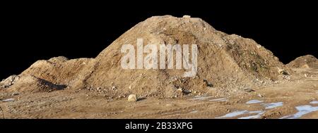 Ein großer Haufen Bausand mit Spuren von Traktorrädern. Isoliert auf weißem Panorama-Schuss im Freien. Stockfoto