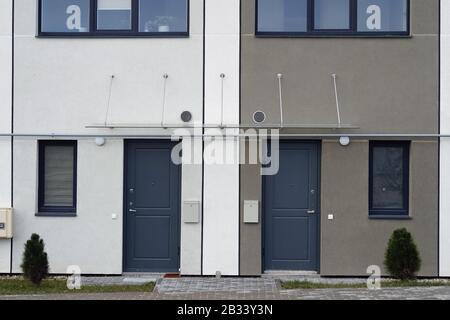 Frontwand eines preiswerten, unbestückten Wohngebäudes mit Türen und Fenstern in Massenproduktion. Natürliche Farben, vereinfachtes Bild Stockfoto