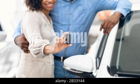 Unerkennbares Paar, Das Den Neuen Autoschlüssel In Der Händlerniederlassung, Panorama, Zeigt Stockfoto