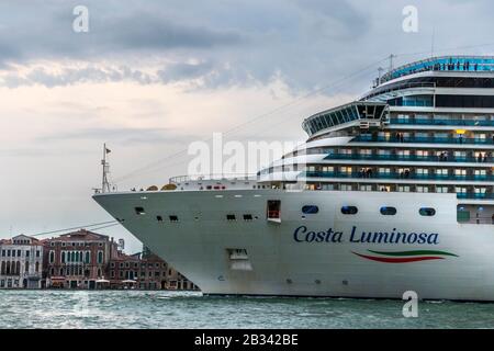 Das riesige Kreuzfahrtschiff Costa Luminosa dominiert die Skyline von Venedig, italien, während es am Abend abfährt. Stockfoto