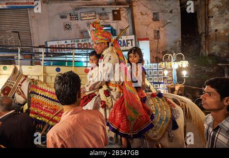 Nachtaufnahme eines Brautzimmers mit Junge und Mädchen auf einem Pferdezug durch die Straßen von Udaipur, Rajasthan, Indien Stockfoto