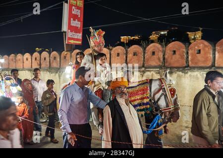 Nachtaufnahme eines Brautzimmers mit Junge und Mädchen auf einem Pferdezug durch die Straßen von Udaipur, Rajasthan, Indien Stockfoto