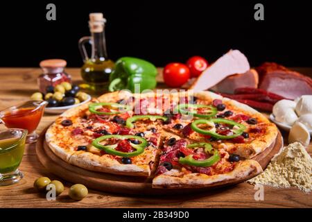 Köstliche Pizza mit Oliven und Würstchen auf Holztisch Stockfoto