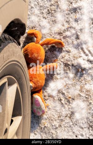 Kinderunfall auf einer Winterstraße, Hase Kaninchen Spielzeug. Tod auf der Straße, Unachtsamkeit und Gefahr. Achtung und Vorsicht. ROADKILL Winter, Konzept, c Stockfoto