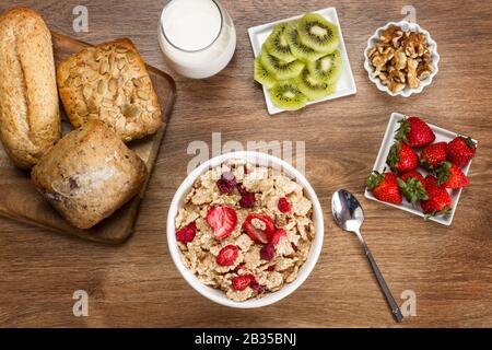 Frühstück mit Müsli, Kiwis und Brot auf einem Holztisch in Draufsicht Stockfoto