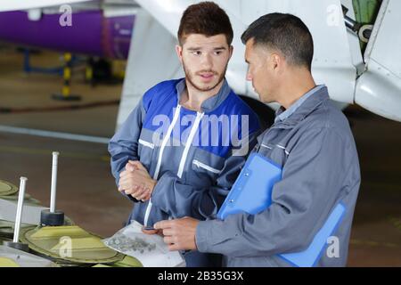 Mechanik mit Beutel mit Befestigungselementen im Flugzeughangar Stockfoto