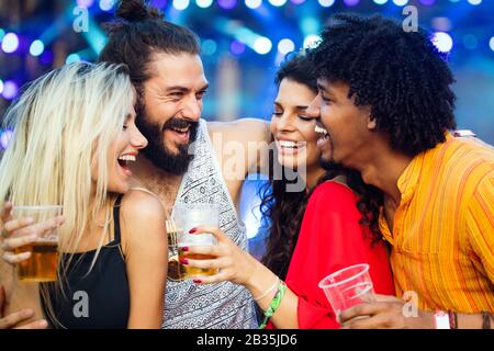 Eine Gruppe glücklicher Freunde, die aushangelt sind und Getränke genießen, Festival Stockfoto