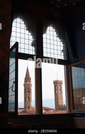 Der Glockenturm der Kirche Badìa Fiorentina (links) und der Turm des Palazzo del Bargello in Florenz, Italien, aus dem mittelalterlichen Fenster betrachtet Stockfoto