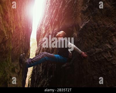 Klettern, lustige Bouldern. Man Athlet auf schönen Felsen. Aktiv gesund. Stockfoto