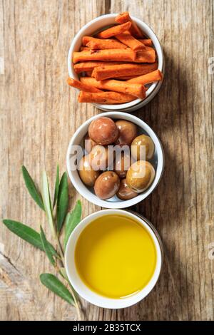 Oliven und Olivenöl auf Holztisch, Draufsicht. Mediterrane Vorspeisen gesund und lecker Stockfoto