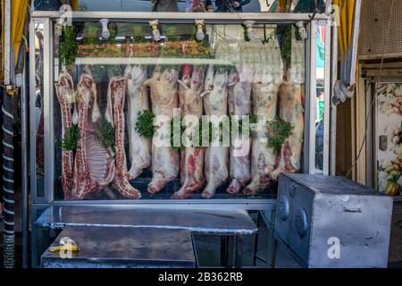 Aqaba, JORDANIEN - 31. JANUAR 2020: Zehn Lammleichen hängen zum Verkauf für Fleisch an der Straßenfront auf dem öffentlichen Stadtmarkt. Schwarz-Weiß-Bild Stockfoto