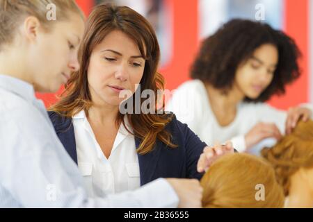 Friseurlehrling bügeln die Haare des Kunden Stockfoto