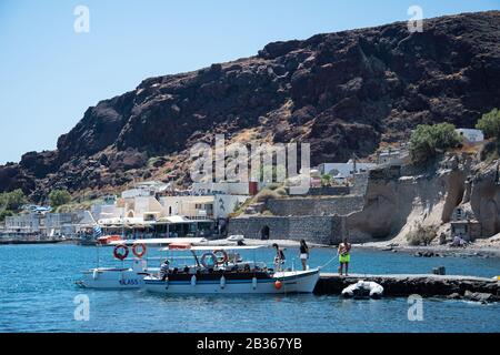 Akrotiri, Griechenland - 19. Juli 2019: Touristen, die ein kleines Ausflugsboot auf dem Dock von Akrotiri boten Stockfoto