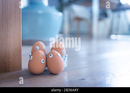 Eine Gruppe von Ostereiern mit lustigen Augen ist am frühen Morgen versteckt, Kinder müssen nach ihnen suchen. Fröhliches Osterkonzept, Osterthema, Hintergrund, Stockfoto