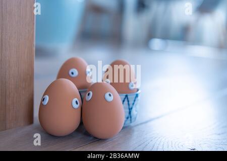 Eine Gruppe von Ostereiern mit lustigen Augen ist am frühen Morgen versteckt, Kinder müssen nach ihnen suchen. Fröhliches Osterkonzept, Osterthema, Hintergrund, Stockfoto