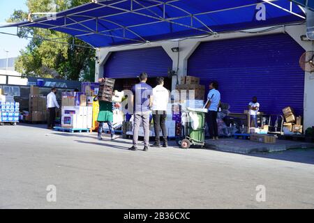 Arbeiter mit Handstapler und Kartons lagern Waren in der Nähe von Lagerräumen im Großhandel. Rückseite des Supermarktes. Entladedock für Waren am Stor Stockfoto