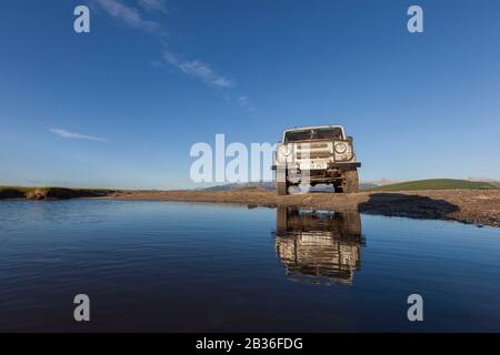 Die Mongolei, die Provinz Khovsgol, die Steppe bei Ulaan Uul, der russische Jeep UAZ 469, der einen Fluss vergiß Stockfoto