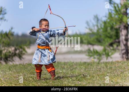 Mongolia, Provinz Khovsgol, Khatgal, Naadam-Festival, kleiner Junge in traditioneller Kleidung, die Bogenschießen betreibt Stockfoto