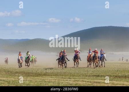 Mongolia, Provinz Khovsgol, Khatgal, Naadam-Festival, Pferderennen, Gruppe junger Teilnehmer galoppieren, grasige Steppe und niedrige Berge im Hintergrund Stockfoto