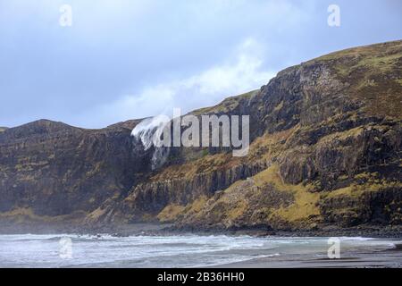 Wasserfall an der Talisker Bay, Skye, Innere Hebriden, scheint aufgrund starker Sturmwinde nach oben zu fließen Stockfoto