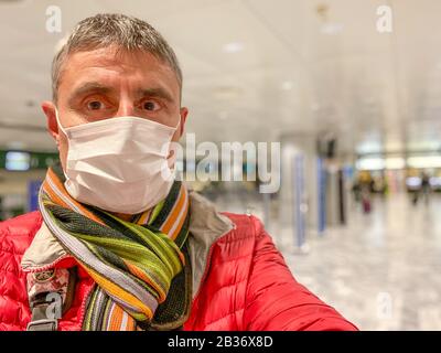 Coronavirus Covid-19 breitet sich über Italien und Europa aus. Mann am Flughafen, der eine Gesichtsmaske trägt, um einen Ansteckungsausbruch zu vermeiden. Stockfoto