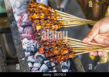 Hand der Person, die Lammshashliks über dem Grillgrill Ubud Bali Indonesia kocht Stockfoto