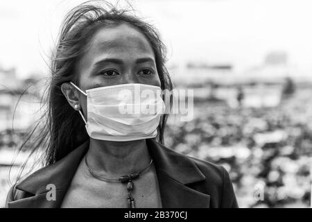 Asiatische Frau, die im Freien Zeit mit hygienischer Maske genießt, um das Virus PM2,5 und Coronavirus zu verhindern. Luftverschmutzung, Konzept des Umweltbewusstseins. Stockfoto