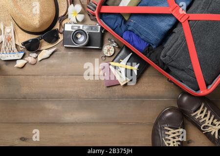 Bereiten Sie Zubehör und Reiseartikel mit Gepäck auf Holzbrett, flacher Lay, Hintergrund von oben vor Stockfoto