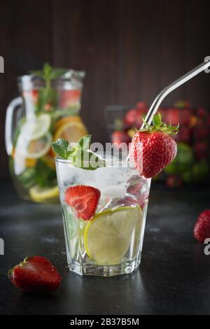 Detox Limonade mit Limone, Orange, Zitrone, Erdbeere in Glas und Krug. Sommer gesunde frische Getränk. Vertikale Ausrichtung. Dunklen Hintergrund. Stockfoto