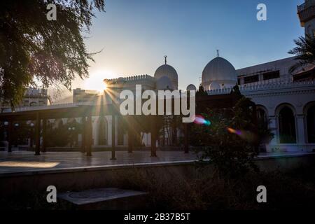 Aqaba, JORDANIEN - 31. JANUAR 2020: Sonne wirft Lichtstreuungen über die schöne weiß getünchte Moschee von Sharif Hussein bin Ali in Aqaba, Jordanien. Wolkenloser klarer Himmel Wintertag. Horizontaler Rahmen Stockfoto