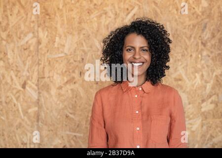 Lächelnde junge Frau, die in ihrer Werkstatt an einer Wand steht Stockfoto