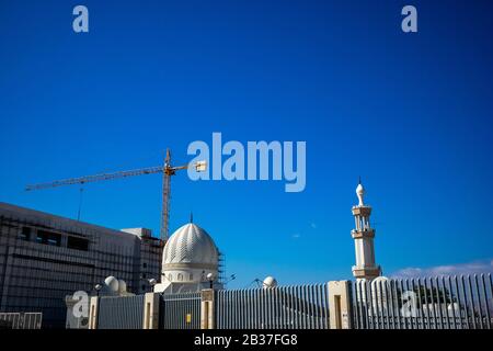 Aqaba, JORDANIEN - 31. JANUAR 2020: Der Bau geht in die Nähe der schönen weiß getünchten Moschee von Sharif Hussein bin Ali in Akaba, Jordanien. Wolkenloser klarer Himmel Wintertag. Horizontaler Rahmen Stockfoto