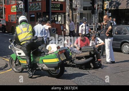 London Ambulance Service Motorrad Sanitäter kommt an, um Motorradkurierfahrer zu unterstützen, die in der Straßenlage für Verkehrsunfälle in London England Großbritannien liegen Stockfoto