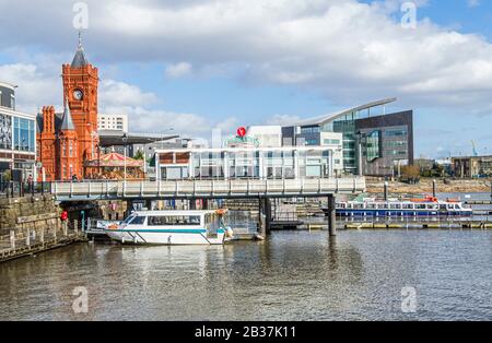 Mermaid Quay in Cardiff Bay, zeigt das Pierhead Building und einen Wassergraben an einem sonnigen Märznachmittag in Südwales. Stockfoto