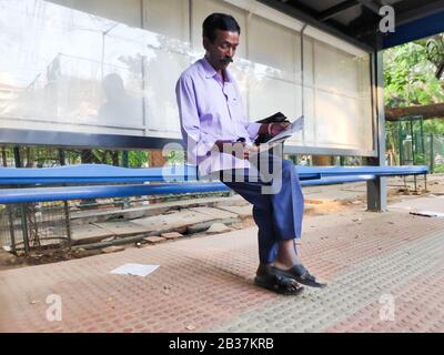 Bangalore, Indien - 17. Mai 2019 - Liest Ein Indianermann eine Zeitung an einer Bushaltestelle in Bangalore, Indien. Stockfoto