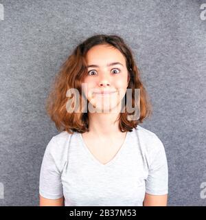 Süßes Teenager-Mädchen mit einem lustigen Gesicht, das mit großen Augen an die Kamera lächelt Stockfoto