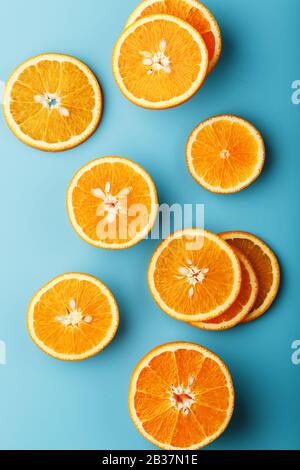 Scheiben und Scheiben aus orangefarbenem Fruchtfleisch auf hellblauem Hintergrund als texturaler Hintergrund, dem Substrat. Vollbildschirm-Flachlage, Draufsicht. Lebensmittelhintergrund. Stockfoto