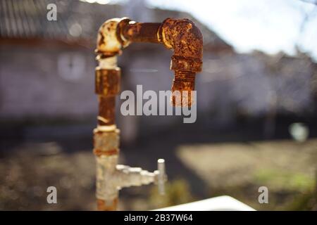 Altes rostiges Wasserhahn in einem ländlichen Hof. Stockfoto