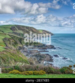 Ein spektakulärer, langer Blick hinunter an der Südostküste Cornwalls von Lansallos nach Polperro, der die grünen Klippen und kleinen Buchten zeigt. Stockfoto