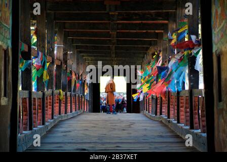 Paro, Bhutan - 18. September 2007: Unidentifizierter Tourist durch Fotoshooting mit einheimischen Bhutanesen in traditioneller Kleidung auf Holzbrücke über den Fluss Paro Stockfoto